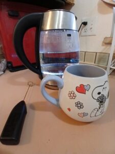Picture electric kettle with water and Snoopy mug.